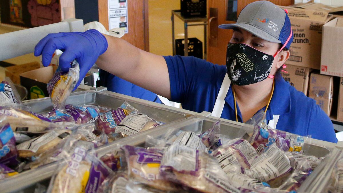 Brenda Linares reaches for sandwiches to pack into lunches at Prairie Queen elementary school...