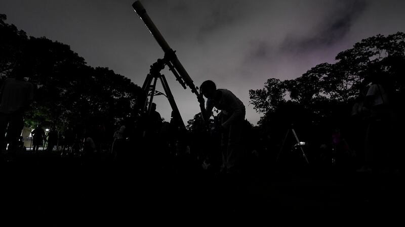 A girl looks at the moon through a telescope in Caracas, Venezuela, on Sunday, May 15, 2022....