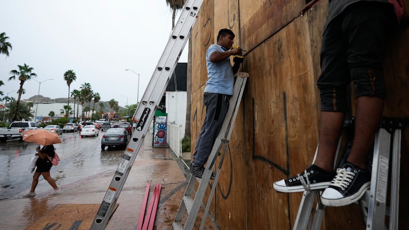 Employees cover the windows of a souvenirs store with wood in preparation for the arrival of...